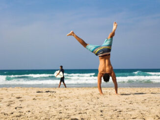 A lean man doing a handstand on the beach showcasing his lean body which in this context symbolises the best fat burners for weight loss